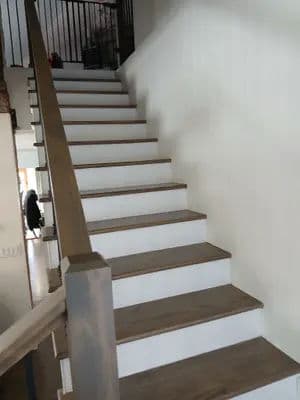 Modern wooden staircase with white risers and natural wood steps in a bright interior.