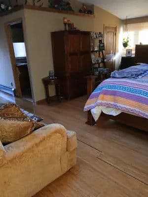Cozy bedroom featuring a wooden bed, colorful bedding, and a stylish armchair.