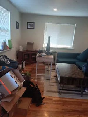 Living room with a blue couch, TV, and cluttered table, showcasing a cozy yet disorganized space.