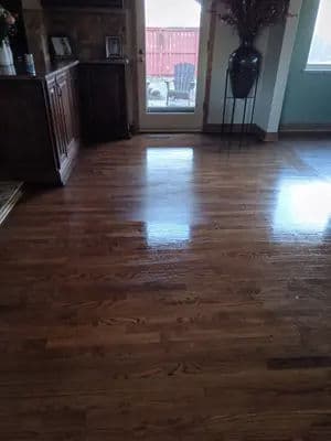 Polished hardwood floor in a bright living room with furniture and a doorway to outside.