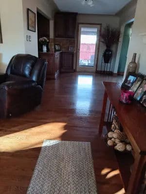 Cozy living room with a leather chair, wooden furniture, and a sunlight-drenched floor.