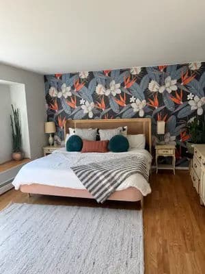 Modern bedroom with floral accent wall, cozy bed, and stylish decor elements.