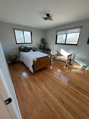 Bright bedroom featuring a wooden bed, natural light, and hardwood floors. Perfect for relaxation.