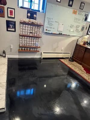Home office with polished black floor, wall-mounted display of baseball memorabilia, and whiteboard.