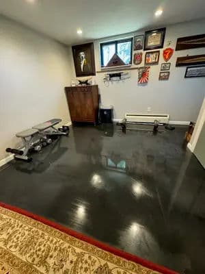 Home gym with weights, workout bench, and wall decor in a well-lit, spacious room.