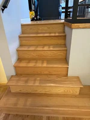 Wooden stairs with a smooth finish leading to an upper level in a modern interior setting.