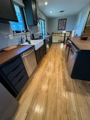 Modern kitchen with wooden floors, stainless steel appliances, and natural light.