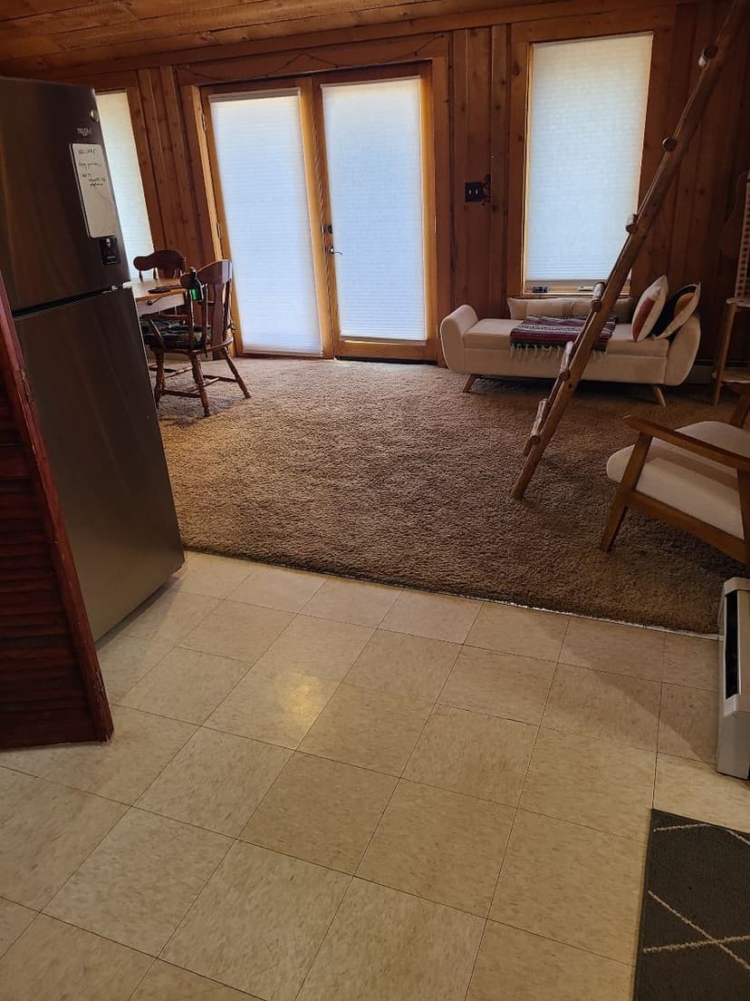 Cozy wooden interior with a living area, kitchen, and large windows for natural light.