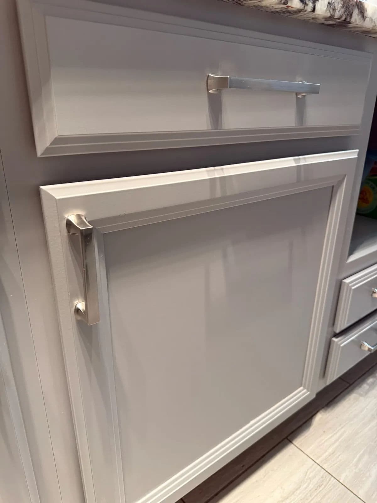 Contemporary kitchen cabinet with sleek silver handles and a polished white finish.
