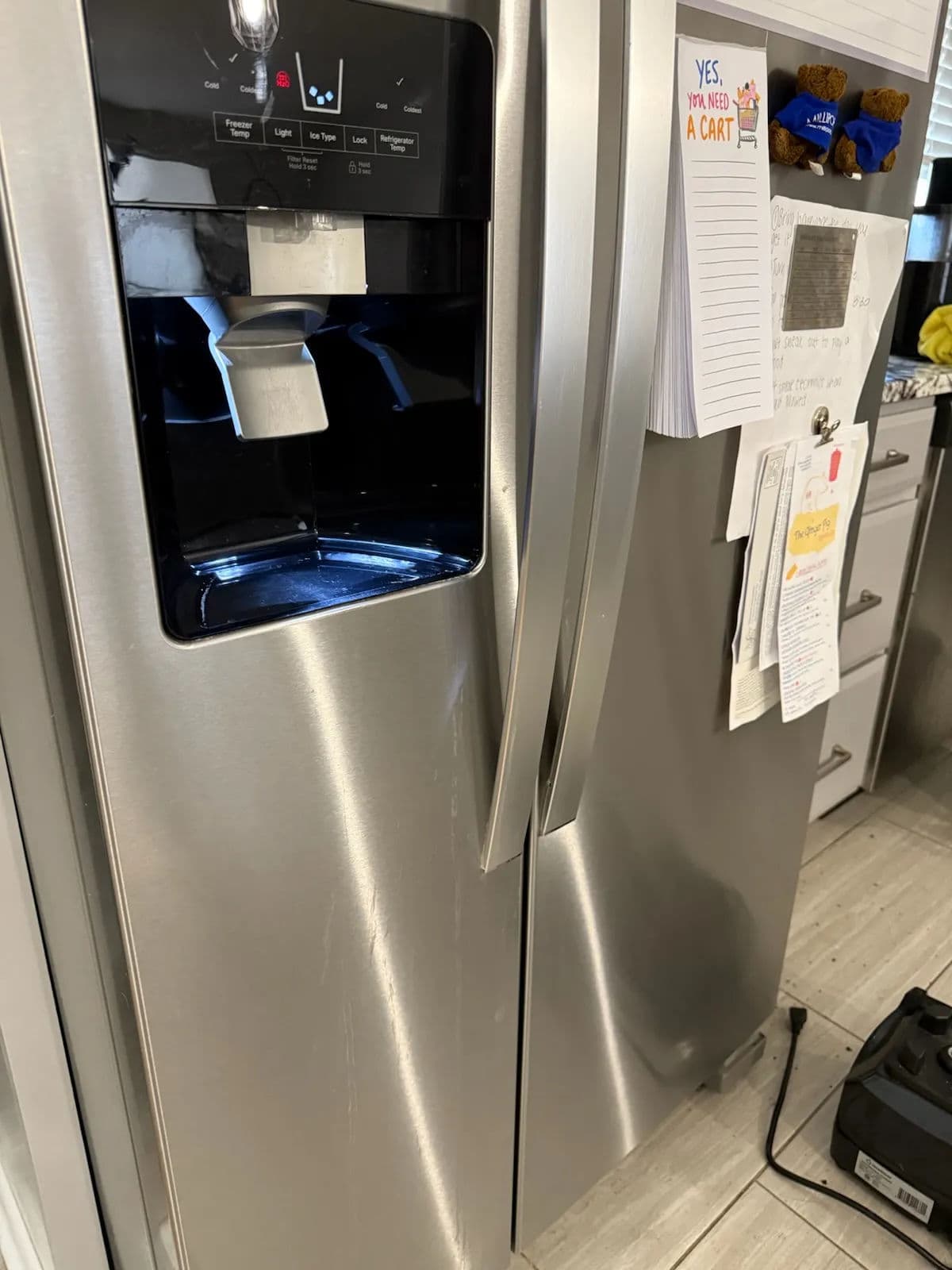 Stainless steel refrigerator with water and ice dispenser, modern kitchen setting.