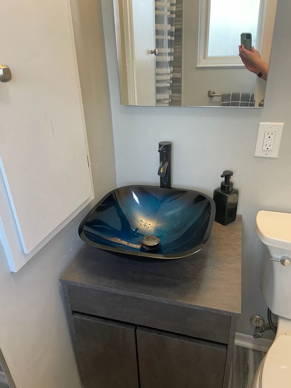 Modern bathroom with a stylish blue glass sink, gray cabinetry, and elegant faucet.