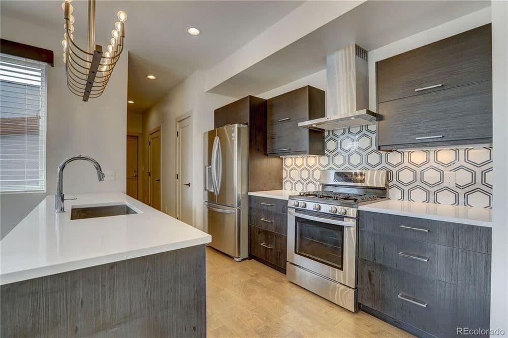 Modern kitchen with stainless steel appliances, hexagon tile backsplash, and ample counter space.