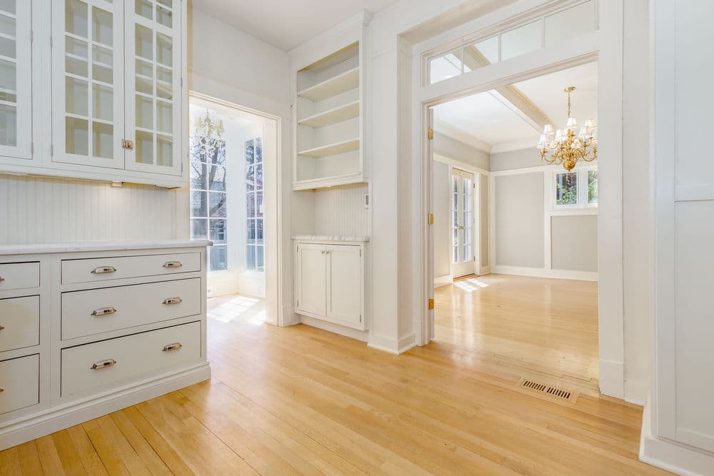 Bright open kitchen and dining area with hardwood floors and elegant chandelier.